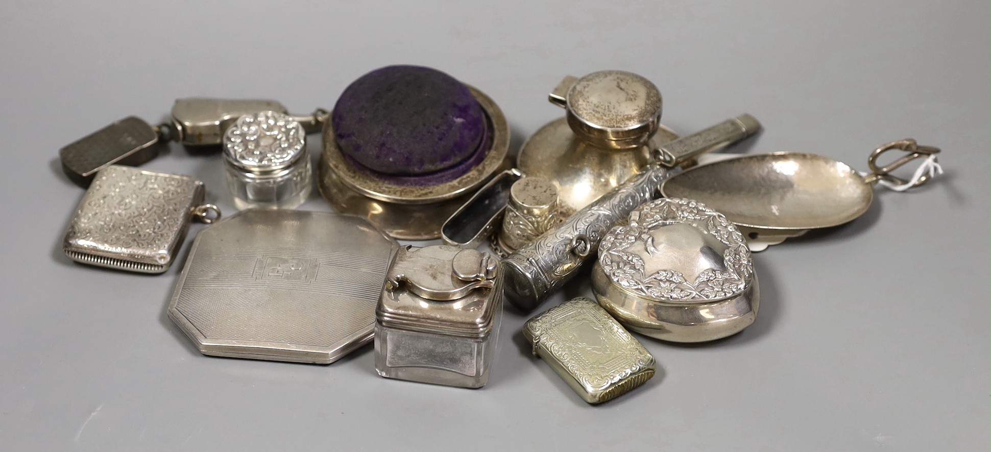 A group of assorted small silver and other items including plated violin vesta case, silver mounted pin cushion, silver heart shaped box, cigarette case, inkwells, planished spoon etc.